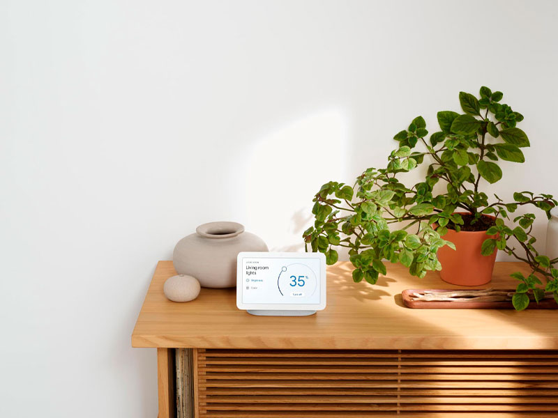 Nest Hub op meubel naast plant
