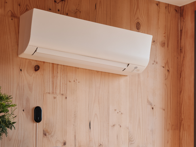 Een mobiele air conditioner in de hoek van een ruimte aangesloten aan een Netatmo Smart Air Conditioner Controller