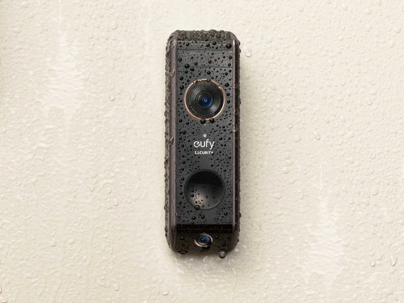 Zwarte Eufy Security videodeurbel met waterdruppels op een lichte muur, een helder beeld van zijn waterbestendigheid. - Slimme Deurbel Problemen