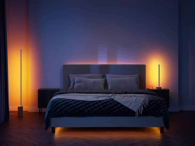 Slaapkamer met slimme verlichting die een warme, rustgevende gloed creëert onder het bed, achter het hoofdeinde en met twee staande lampen, essentieel voor 'Slaap Beter, Leef Beter: De Rol van een Slimme Slaapkamer'.
