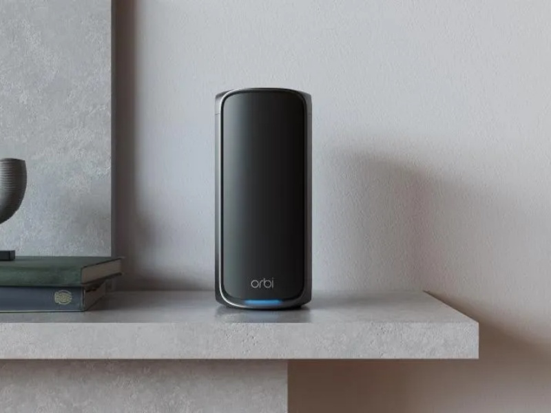 Zwarte Orbi mesh WiFi router met blauwe indicatorlamp, staand op een plank, ideaal voor het oplossen van wifi problemen en het verbeteren van netwerkbereik.