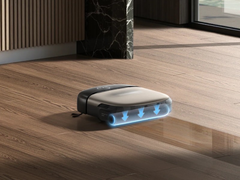 Een antracietkleurige Eufy Omni S2 robotstofzuiger met zilveren bovenkant dweilt een lichtbruine houten vloer. Blauwe pijlen visualiseren de natte reinigingsactie, die een glimmende streep achterlaat.