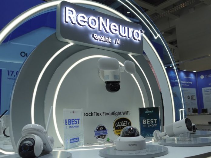 Helder verlichte Reolink stand op IFA 2025 met een opvallend wit, gebogen display tegen een felblauwe achtergrond. Centraal prijkt een oplichtend wit 'ReoNeura Reolink AI' bord, omringd door diverse witte beveiligingscamera's, waaronder dome-, bullet- en floodlightmodellen. Meerdere 'Best in Show' en 'IFA Innovation Award 2025' prijzen zijn zichtbaar op de presentatietafel.