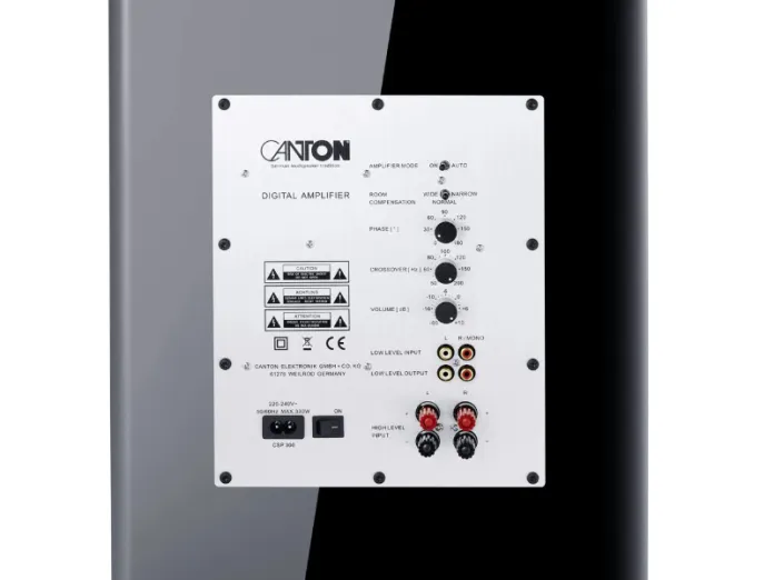 Image: Witte digitale versterkerplaat van een Canton subwoofer, gemonteerd op een glanzende, donkere behuizing, met regelaars voor volume, crossover, fase, en diverse rode/gele RCA- en luidsprekerterminals.