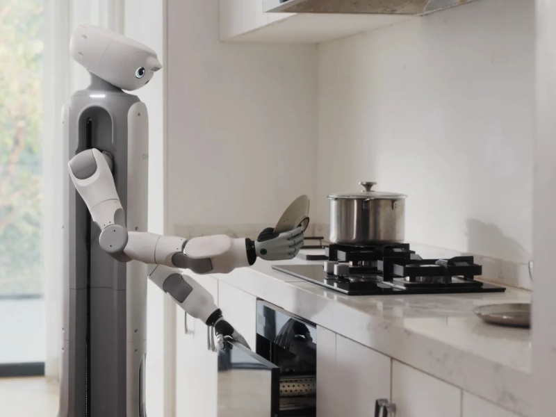 Grijze en witte humanoïde robot voert kooktaken uit in een moderne, lichte keuken, wat de CES 2026 verwachtingen voor huishoudelijke robots illustreert.