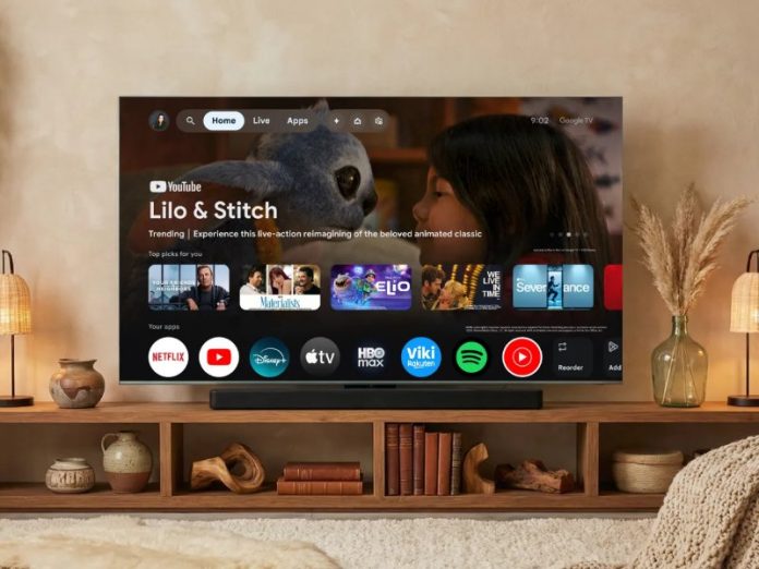 Zwart Google TV-scherm toont de Gemini update interface met app-iconen en 'Lilo & Stitch' content, staand op een lichtbruin houten meubel in een gezellige, beige kamer met groene hangplanten.