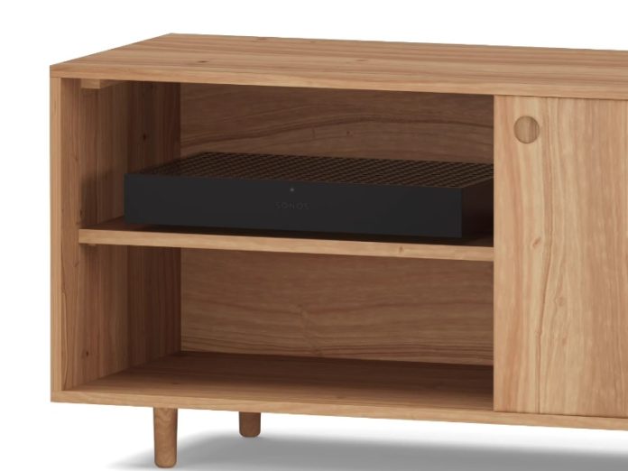 Zwarte Sonos component in een open vak van een lichte eikenhouten kast.