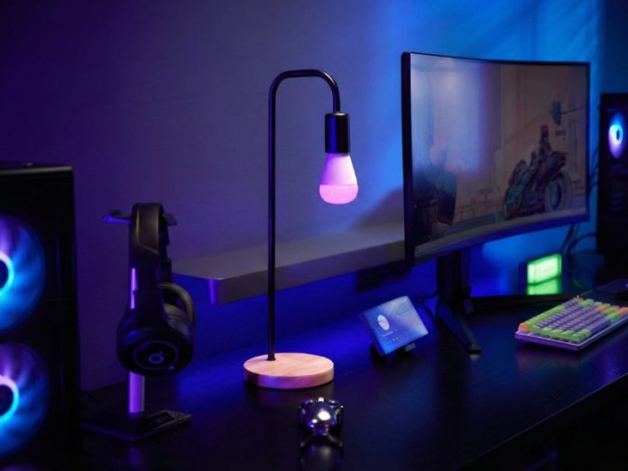 Zwarte bureaulamp met roze E27 slimme lamp op een bureau, verlicht door paars en blauw ambient licht, te zien in de review 