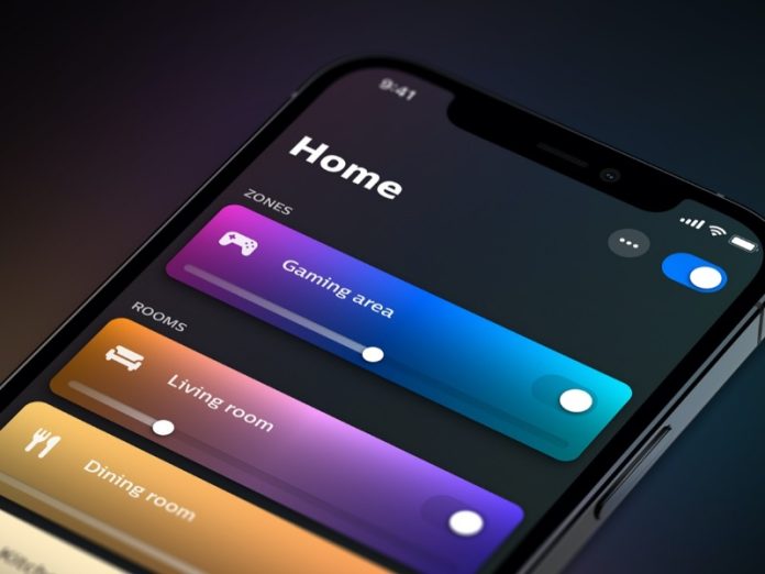 Close-up van de Philips Hue AI app op een smartphone in donkere modus. Dynamische, gegradeerde kleurschuifbalken tonen lichtinstellingen; de actieve 'Gaming area' zone loopt van magenta naar cyaan.