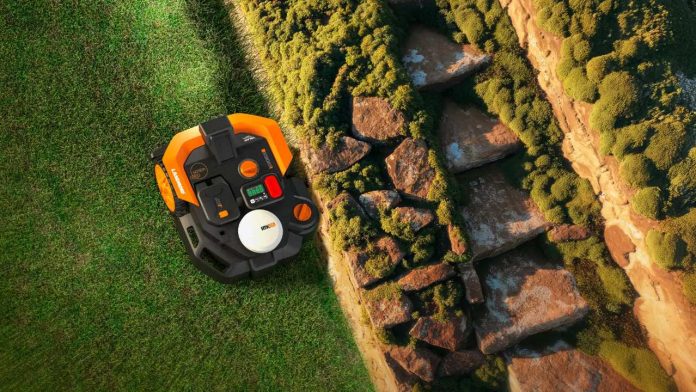 Bovenaanzicht van een oranje en zwarte robotmaaier die nauwkeurig langs een stenen border op een groen gazon maait, een voorbeeld van de beste robotmaaiers voor strakke randen.