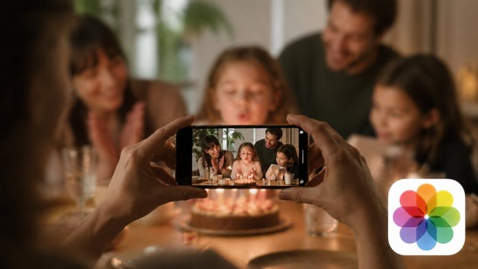 Een sfeervolle weergave van een gezin dat een verjaardag viert, vastgelegd op een smartphone om de Apple Foto's AI update te demonstreren, met het herkenbare kleurrijke logo in de hoek.