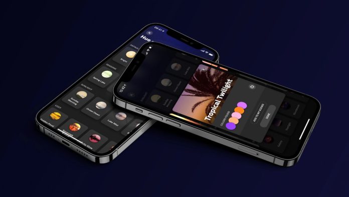 Twee iPhones met de Philips Hue App tegen een donkerblauwe achtergrond, die verschillende lichtscènes tonen zoals 'Tropical Twilight' met een palet van paars, roze en oranje.