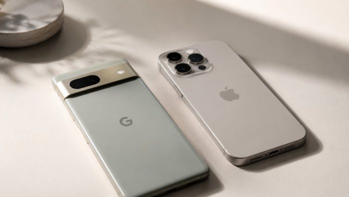 Een saliegroene Google Pixel met een gouden camerabalk en een beige iPhone Pro liggen naast elkaar op een neutraal oppervlak, wat de verbeterde iOS 26.5 RCS encryptie tussen beide toestellen symboliseert.