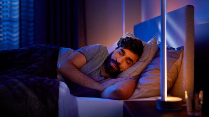Een man die rustig slaapt in een donkere kamer, verlicht door de zachte en warme gloed van jetlag slimme verlichting om het slaap-waakritme te bevorderen.