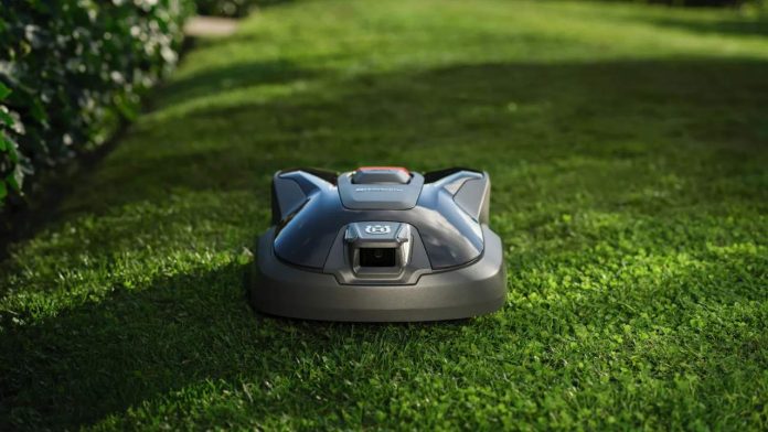 Een moderne donkergrijze Husqvarna robotmaaier op een zonnig groen gazon, waarbij de efficiëntie bepalend is voor het stroomverbruik van de robotmaaier.