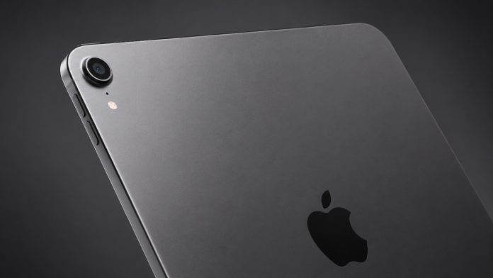 Een close-up van de achterkant van een spacegrijze iPad, waarop het glanzende zwarte Apple-logo en de cameramodule duidelijk zichtbaar zijn tegen een donkergrijze achtergrond.