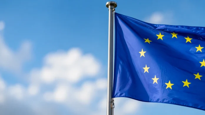 Een wapperende Europese vlag tegen een helderblauwe lucht met witte wolken in het kader van de Digital Markets Act cloud smart home.