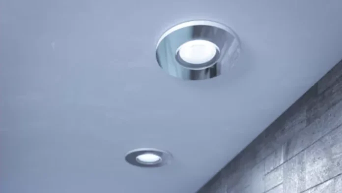 Moderne zilverkleurige hue inbouwspots die een helder licht verspreiden vanaf een strak wit plafond in een eigentijdse ruimte.