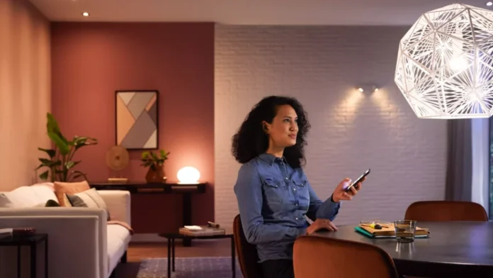 Een vrouw bedient de sfeervolle HUE verlichting in haar modern ingerichte woonkamer met een smartphone.
