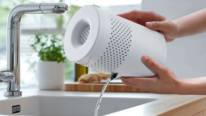Een witte draagbare ventilator slaapkamer wordt boven een gootsteen geleegd om het waterreservoir te verversen.