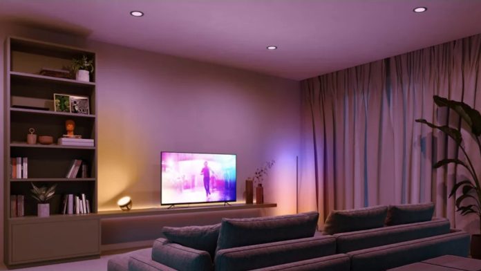 Een sfeervolle woonkamer voorzien van een Philips Hue Slim Recessed upgrade, met paarse en roze verlichting op de muur achter de tv en subtiele inbouwspots in het plafond die een warme ambiance creëren.