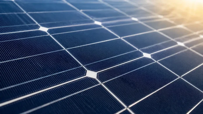 Close-up van moderne blauwe zonnepanelen met een reflectie van warm zonlicht op het oppervlak.