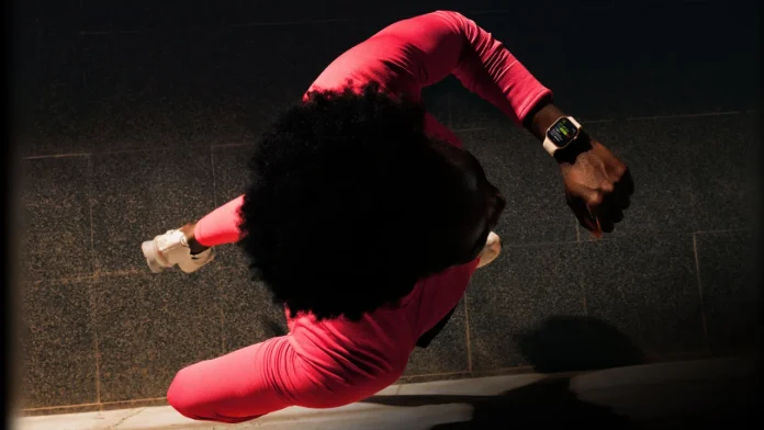 Bovenaanzicht van een hardloper in felroze sportkleding die het moderne Apple Watch Series 12 ontwerp om de pols draagt tijdens een workout.