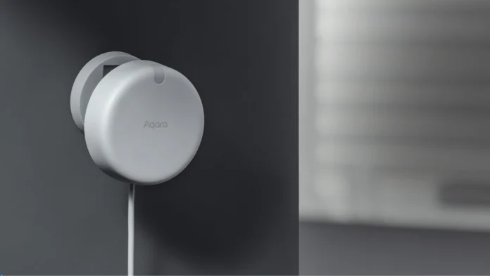 Een compacte witte Aqara Presence Sensor FP2 is aan een donkere muur bevestigd voor nauwkeurige aanwezigheidsdetectie.
