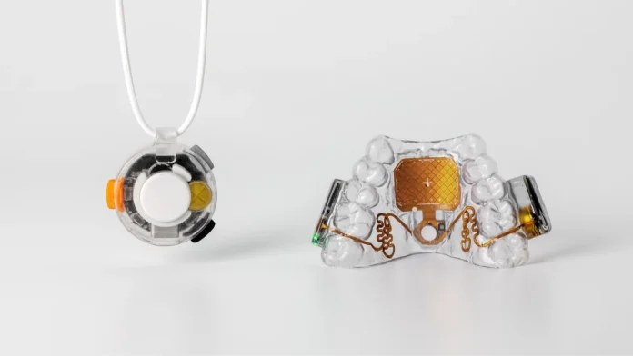 Een gedetailleerde weergave van de Augmental MouthPad, een transparant mondstuk met geïntegreerde elektronica, getoond naast een bijbehorend rond controleapparaat op een witte achtergrond.