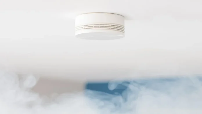 Een witte, compacte rookmelder is aan een strak wit plafond bevestigd als voorbeeld van de beste slimme rookmelders 2026.