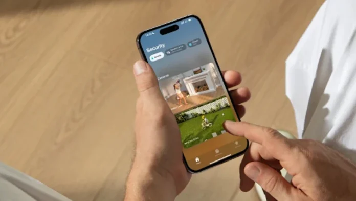 Een persoon beheert de beveiliging van hun slimme woning met HomeKit Secure Video Apple Intelligence op een iPhone die live camerabeelden van de tuin en woonkamer toont.