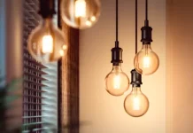 Drie decoratieve Philips HUE filamentlampen hangen aan zwarte snoeren en verspreiden een warme, sfeervolle gloed in een modern interieur.