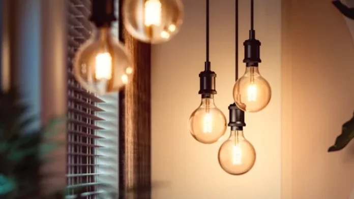 Drie decoratieve Philips HUE filamentlampen hangen aan zwarte snoeren en verspreiden een warme, sfeervolle gloed in een modern interieur.