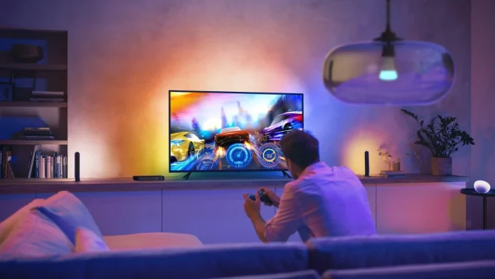 Een gamer geniet van een meeslepende race-ervaring in een woonkamer die sfeervol wordt verlicht door de dynamische kleuren van Philips Hue.