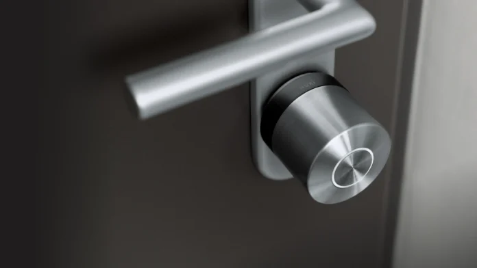 Een modern zilveren deurslot gemonteerd op een donkere deur voor wie online een Nuki Smart Lock vergelijken wil.
