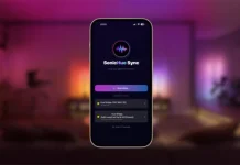 Een smartphone toont de SonicHue Sync Philips Hue-app terwijl deze zoekt naar verbindingen in een sfeervol paars verlichte woonkamer.