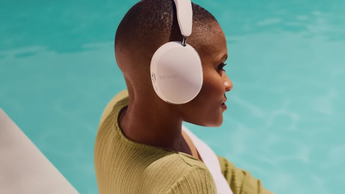Een vrouw met kortgeschoren haar draagt een witte sonos hoofdtelefoon bij een helderblauw zwembad in de zon.
