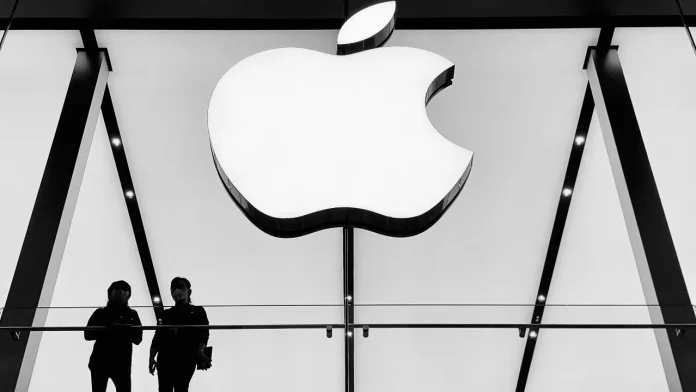 Groot verlicht Apple logo in een moderne winkel met twee mensen in silhouet.