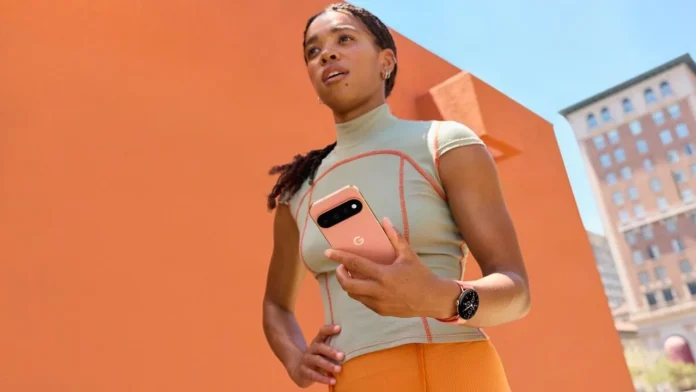 Vrouw met een roze Google Pixel telefoon en smartwatch voor een oranje achtergrond.