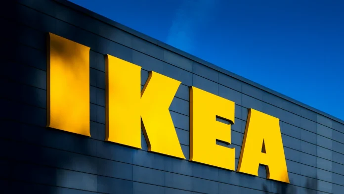 Groot geel Ikea logo op een blauwe gevel van een winkelpand tegen een helderblauwe lucht.