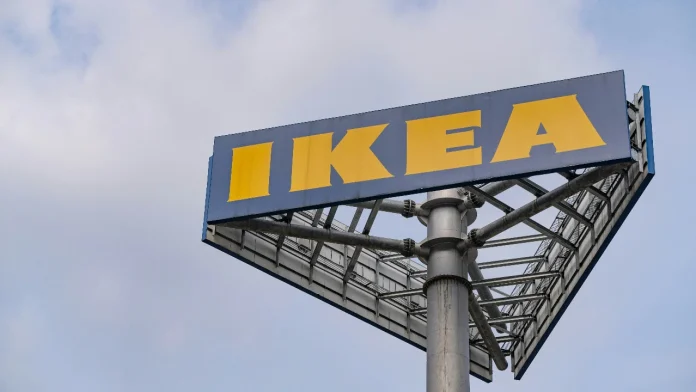 Groot blauw en geel Ikea reclamebord op een hoge paal tegen een bewolkte lucht.