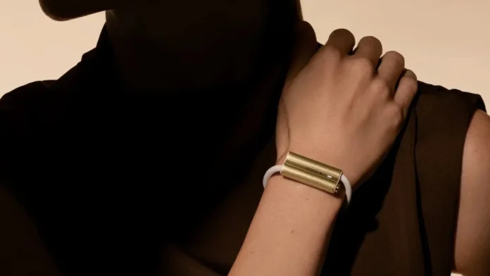 Gouden luffu link wearable om de pols van een vrouw in een artistieke setting.