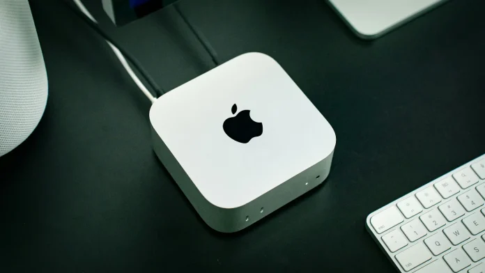 De nieuwe Mac mini M5 op een donker bureau met een wit toetsenbord en kabels.