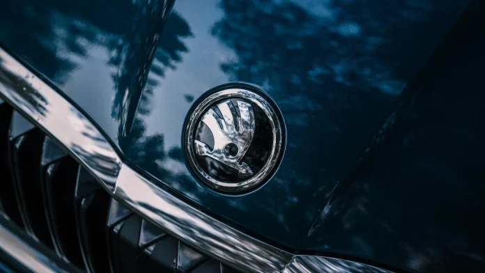 Detailopname van het zilveren Skoda logo op de motorkap van een donkerblauwe auto.