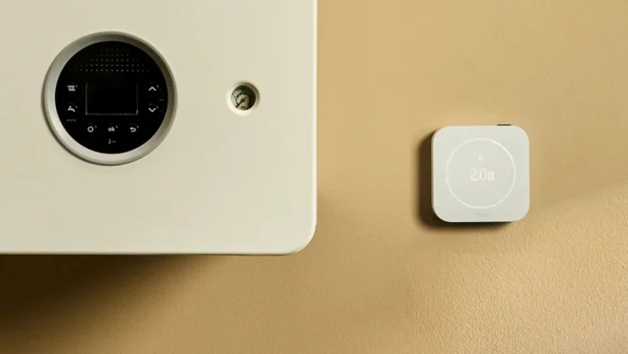 tado slimme thermostaat naast een witte CV-ketel op een beige muur.