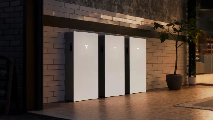 Drie strakke witte Tesla Powerwall 3P thuisbatterijen zijn gemonteerd aan een betegelde wand in een modern vormgegeven ruimte met sfeerverlichting.