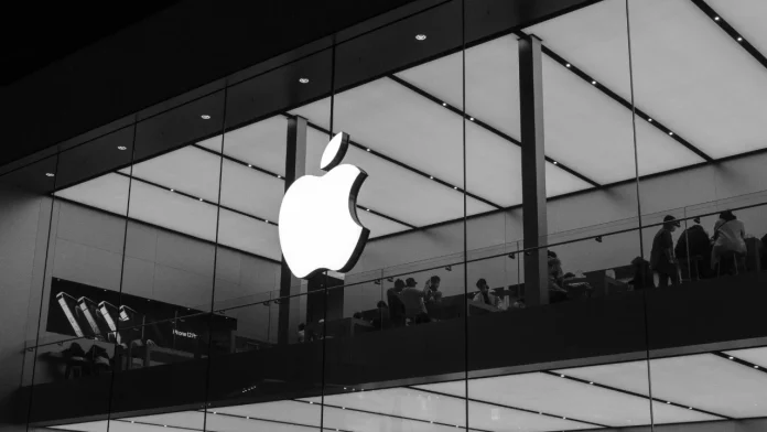 Verlicht Apple logo op de glazen gevel van een moderne winkel met klanten binnen in zwart-wit.