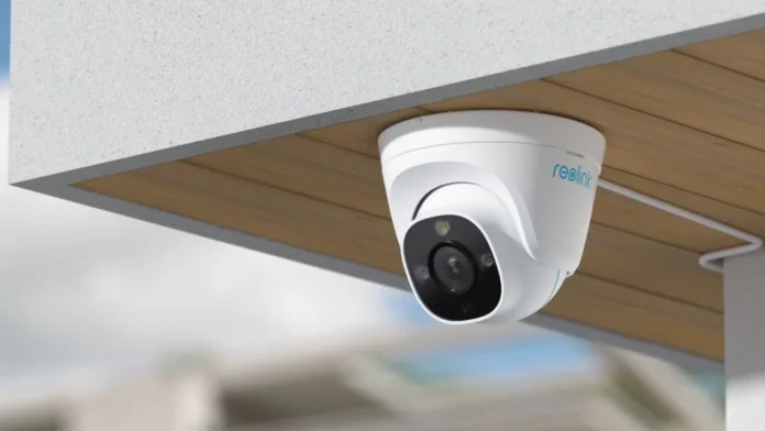 White Reolink dome camera mounted on a wooden soffit for outdoor home security and surveillance.