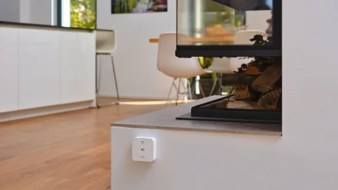 Witte CO2-meter aan de wand in een modern interieur bij een open haard.