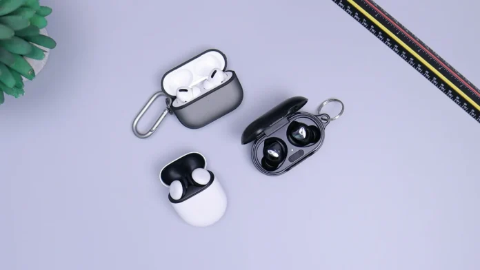 Drie verschillende draadloze earbud sets in oplaadcases op een grijze achtergrond.